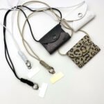 drei Varianten der Handy-Lanyard mit Portemonnaie. Eines in weiß, eines in schwarz und eines in einem leopardenmuster